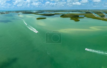 Boats zip across the ocean water in the Gulf of Mexico in Southwest Florida in an aerial view.