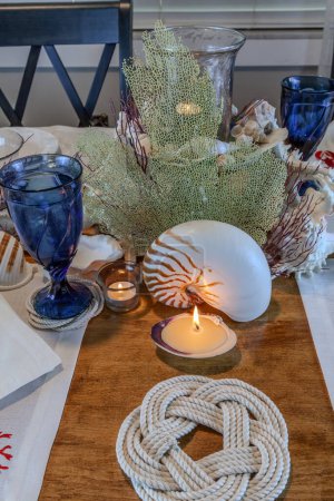 Seashell and candle decoration on a nautical table setting with natural colors and deep blue.