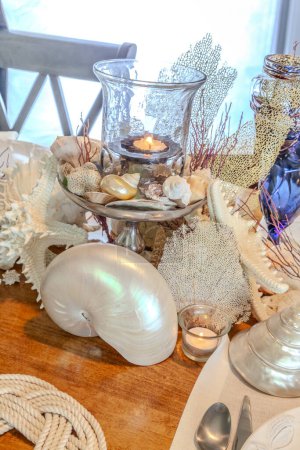 Seashell and candle decoration on a nautical table setting with natural colors and deep blue.
