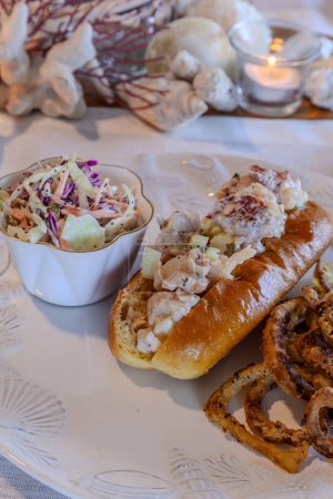 Lobster salad in a fresh brioche roll with homemade fried onion rings and coleslaw and a glass of cold lemonade.