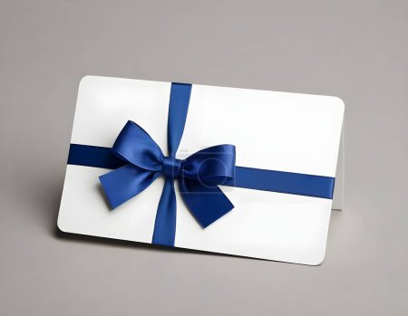 Une carte cadeau blanche ornée d'un ruban bleu satiné est centrée sur une toile de fond neutre gris clair. La carte offre amplement d'espace pour un message personnalisé et est parfaite pour les occasions spéciales.