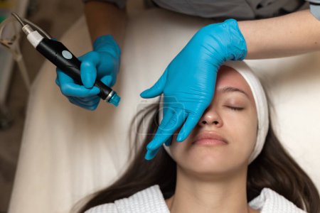 Facial Skin Treatment. Woman Receiving Cosmetic Mask In Beauty Salon