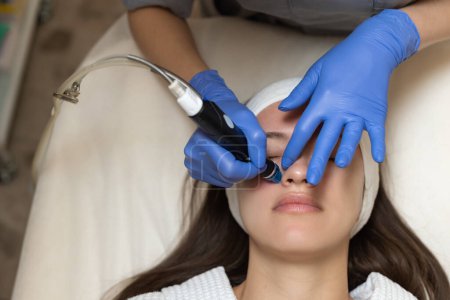 Facial Skin Treatment. Woman Receiving Cosmetic Mask In Beauty Salon