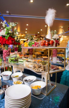 Lassen Sie sich mit einer köstlichen Auswahl an Salaten, Gemüse und Snacks verwöhnen, die kunstvoll auf einem Buffettisch präsentiert werden. Perfekt für Veranstaltungen, Partys oder Versammlungen. Vereinzelt auf blauem Hintergrund.