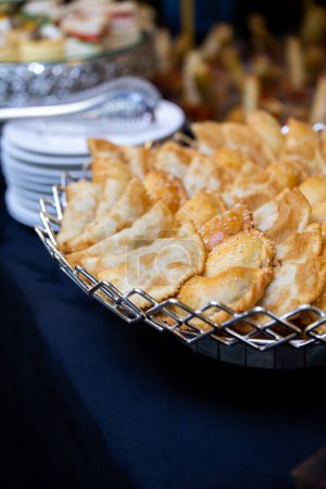 An assortment of freshly baked pastries are arranged on a silver platter and placed on a dark blue tablecloth, ready to be served.