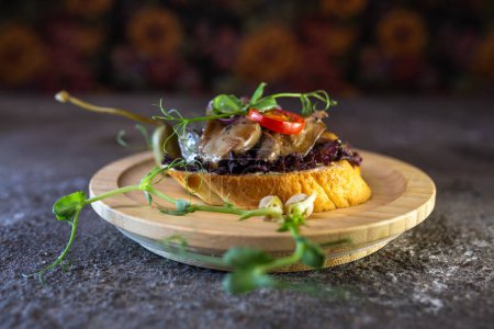 Assiette rustique en bois avec sandwich ouvert au filet de b?uf et champignons rôtis, garnie de germes frais.