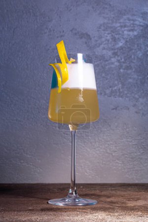 Sofisticado cóctel de champán con toque de limón en la mesa de madera, fondo azul. Perfecto para ocasiones especiales y momentos de brindis.