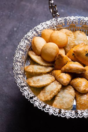 An assortment of delicious pastries, including baklava, borek, and bourekas, is artfully arranged on a silver platter.