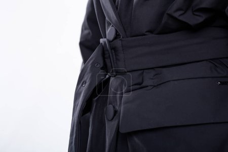 Foto de Una mujer ajusta el cinturón de una chaqueta negra con ajuste delgado y cuello clásico, creando un aspecto elegante y sofisticado traje de negocios. - Imagen libre de derechos