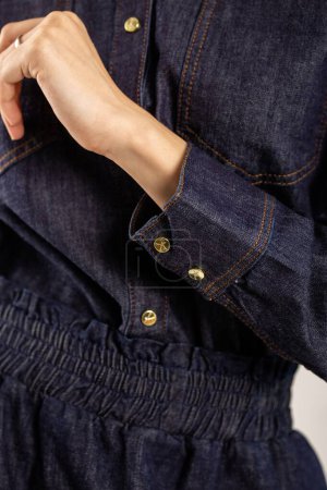 Blue denim shirt with gold buttons. Collar, long sleeves, golden cuff buttons, front fastened with six gold buttons.