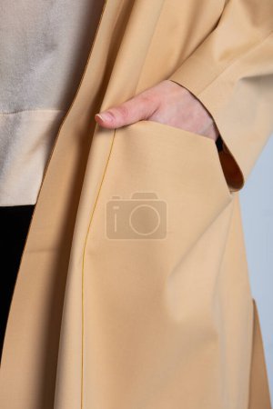 A model wearing an elegant beige coat with large front pockets. The coat is perfect for staying warm and stylish in the fall and winter.