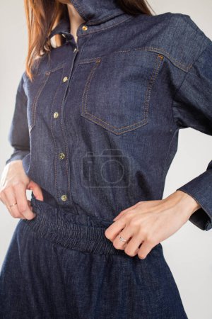 Eine junge Frau in blauem Jeanshemd mit Kragen und langen Ärmeln. Passend zur Taille mit einem dehnbaren Bund.