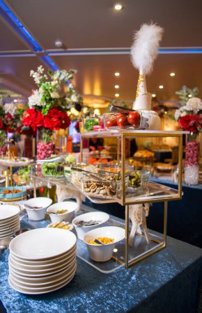 Offrez-vous une délicieuse gamme de salades, légumes et collations, présentés avec art sur une table à buffet. Parfait pour les événements, fêtes ou rassemblements. Isolé sur fond bleu.