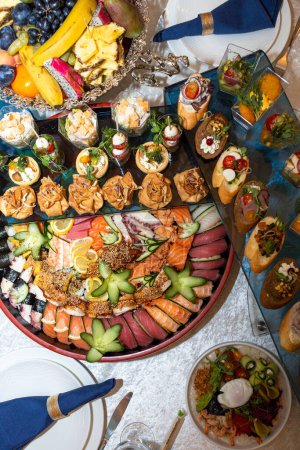 A buffet in a chic hotel with seafood, sushi, salads, fruits and pastries.