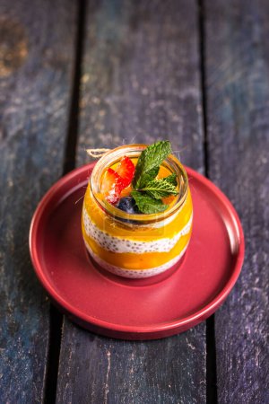 Pouding aux graines de chia avec mangue, baies mélangées, lait, yaourt grec, fruits variés et miel. Délice d'inspiration tropicale pour un délice estival rafraîchissant.