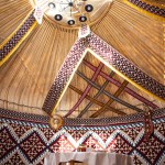 Interior of a kazak yurt with felt carpets, furniture, and a table. Traditional nomadic dwelling with white tablecloth.