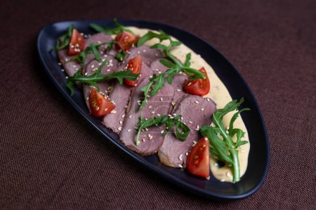 Photo for Savor the succulent flavors of pan-seared duck breast served with a vibrant arugula salad topped with cherry tomatoes, sprinkled with toasted sesame seeds, and drizzled with a luscious creamy sauce. - Royalty Free Image