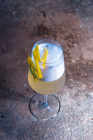 Anspruchsvoller Champagner-Cocktail mit Zitronengeschmack auf Holztisch, blauer Hintergrund. Perfekt für besondere Anlässe und Trinkmomente.