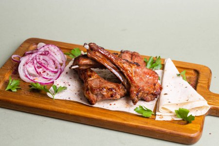 Delicious and juicy grilled lamb ribs with herbs and spices, served on a wooden board. Perfect for a hearty meal or a party with friends.