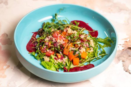 Salad with pumpkin, lettuce, tomatoes, and quinoa. Drizzle with beet sauce and decorate with herbs. Isolated on a white background.