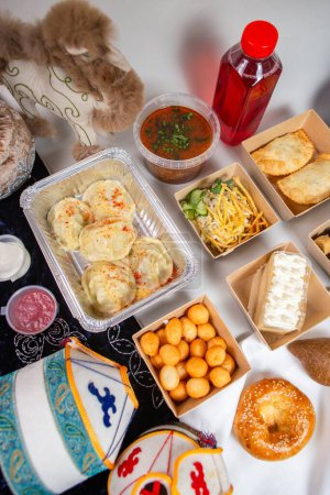 An assortment of Uzbek food including dumplings, soup, pastries, and bread with traditional decor and a drink on a white background.