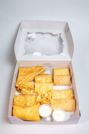 12 small pancakes with sweet and savory fillings in a white box. Options include cheese, potato, and meat. Perfect for breakfast or snack.