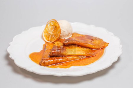 Indulge in a tempting dessert of crepes bathed in a zesty orange sauce and crowned with creamy ice cream for a delightful treat.