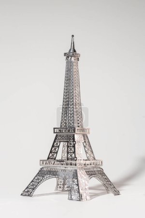 Metal Eiffel Tower cutout on white background. Lattice design highlights skill and precision, creating intricate pattern.