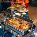 A buffet food warmer filled with delicious beef. The beef is cooked to perfection and is served with a variety of sauces and sides.