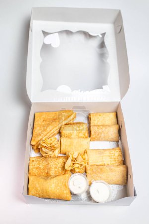 12 kleine Pfannkuchen mit süßen und herzhaften Füllungen in einer weißen Schachtel. Zur Auswahl stehen Käse, Kartoffeln und Fleisch. Perfekt für Frühstück oder Snack.