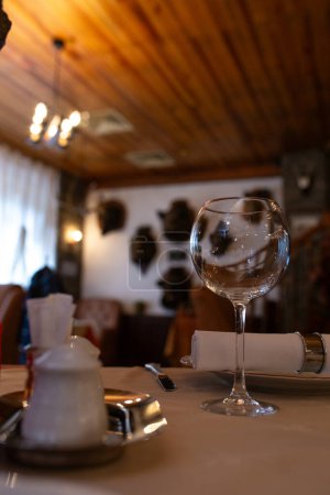The image shows an elegant restaurant table setting with wine glasses and a bottle on the table with a blurred background of the restaurant.