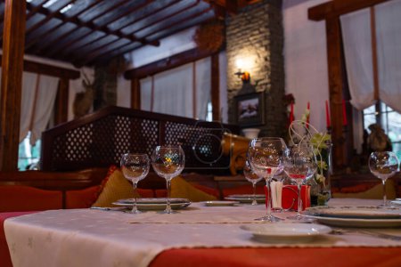 Das Bild zeigt einen eleganten Restauranttisch mit Weingläsern und einer Flasche auf dem Tisch mit einem unscharfen Hintergrund des Restaurants.