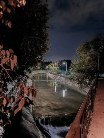 Foto de larga exposición de un río de la ciudad por la noche, con agua reflectante suave y luces de la ciudad brillando brillantemente.