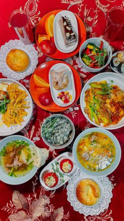 Vista superior de los platos tradicionales uzbekos en una mesa con mantel rojo. Sopas, ensaladas, platos principales, pasteles, bebidas.