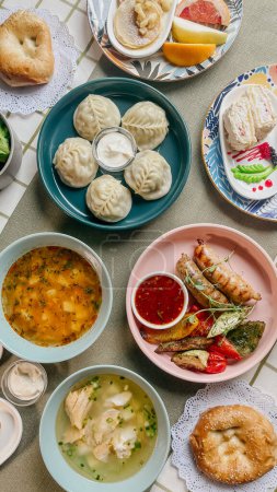 Una variedad de comida uzbeka en una mesa que incluye albóndigas, sopa, ensalada, pasteles y pan con mermelada y mantequilla.