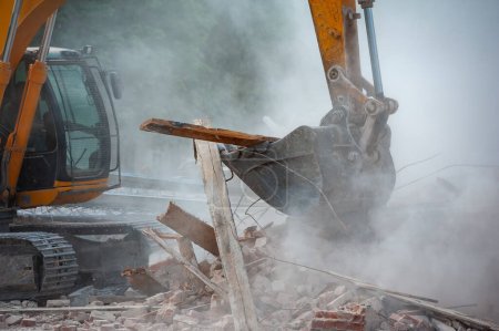 Foto de Demolición del edificio. La excavadora rompe la vieja casa. Liberar espacio para la construcción de un nuevo edificio. - Imagen libre de derechos