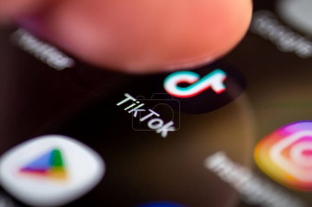 Photo for London. UK- 12.31.2022. A person pressing on the symbol, icon of the social media application Tik Tok on the screen of a smartphone. - Royalty Free Image