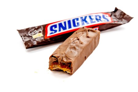 Foto de London. UK-02.12.2023. A packet of Snickers chocolate bar with the chocolate outside the packet isolated in white. - Imagen libre de derechos
