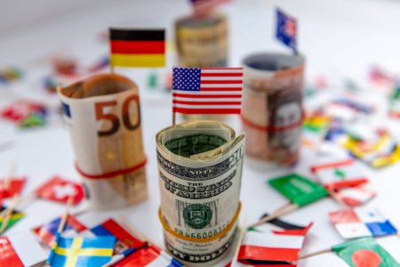 Foto de Rolled bundles of major currencies and country flags with the US Dollar and American flag in front. Dollar hegemony concept. - Imagen libre de derechos