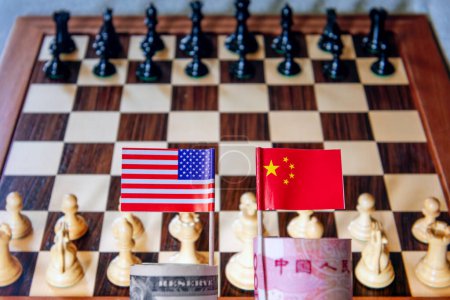 Foto de Un rollo de USD y Yuan Chino con la bandera nacional de cada país con un tablero de ajedrez en el fondo. Un concepto global de dominancia del comercio financiero competencia y conflicto. - Imagen libre de derechos