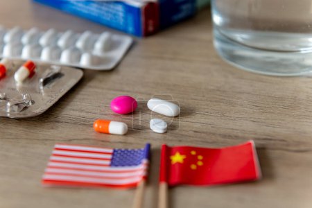A pharmaceutical, medical competition, conflict, concept with the American and Chinese flags and various medicines on a desk.