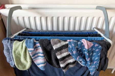 Téléchargez les photos : Séchage des vêtements de blanchisserie sur une grille fixée à un radiateur de chauffage domestique. - en image libre de droit