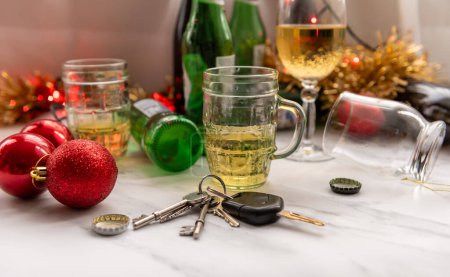 A Christmas, festive drink driving concept with a set of car keys on a table full of alcoholic drinks and decorations.