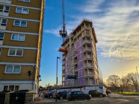 Foto de Londres, Reino Unido 12.20.2023. Un edificio alto en construcción junto a bloques más antiguos de apartamentos de gran altura para viviendas sociales por la autoridad local Consejo de Haringey. - Imagen libre de derechos