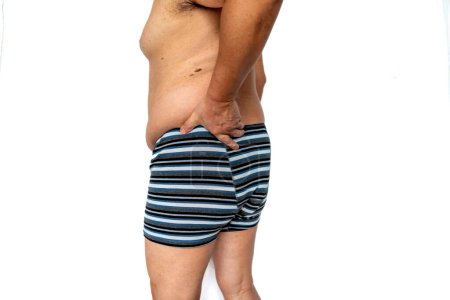 An older man suffering from sciatica back pain on the left side isolated in white.