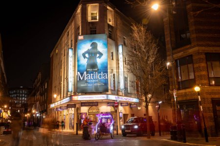 Photo for London. UK- 02.04.2024. A night time exterior view of the Cambridge Theatre showing the facade, entrance and the billboard for the Matilda musical. - Royalty Free Image