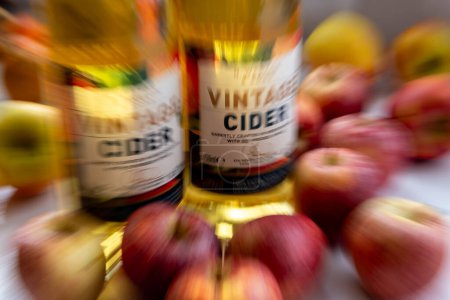 A zoom burst background of bottles of vintage cider surrounded by apples.