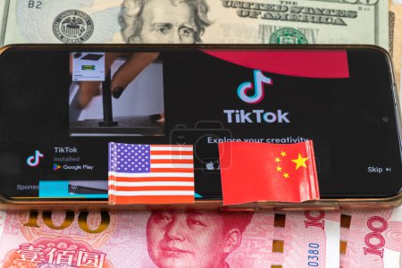 Photo for London. UK- 04.26.2024. A TikTok ban, technology political economic concept. A mobile phone with the Chinese app on the screen on top of Chinese and US bank notes and the national flags on top. - Royalty Free Image