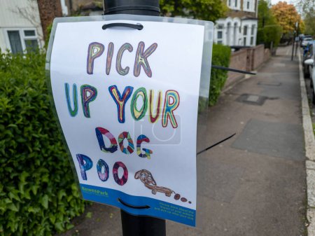 Téléchargez les photos : Londres. Royaume-Uni 04.23.2024. Un avis de rue sur un lampadaire d'un projet de quartier disant aux promeneurs de chiens de ramasser leur crotte de chien dans la rue. - en image libre de droit
