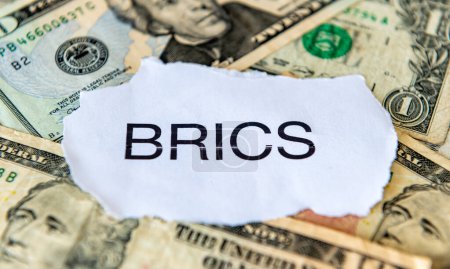 A dedollarisation concept with the BRICS on top of a pile of US dollar bills.